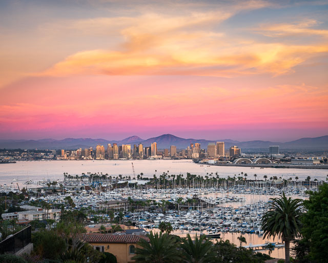 San Diego skyline from Point Loma. In the foreground you can see Harbor Island marina and the middle has downtown. The sky is a gorgeous a mix of pink and yellow tones.