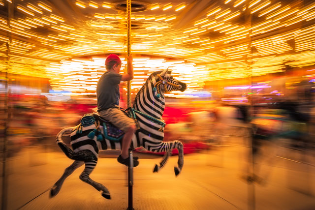 A young boy riding the merry-go-round at the San Diego fair.